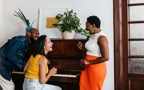 Diverse group of friends sharing laughter while playing the piano