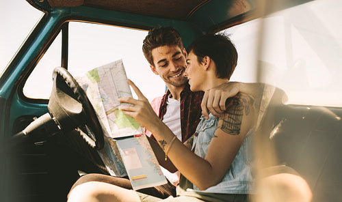 Young travellers on a road trip looking at map