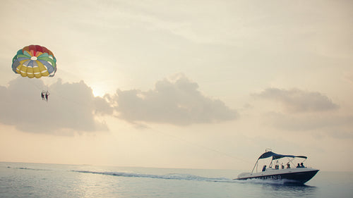 People parasailing above the beautiful ocean at sunset