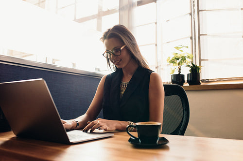 Young woman working on laptop computer in office.