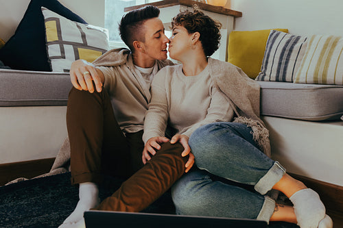 Sweet queer couple going in for a kiss in the living room