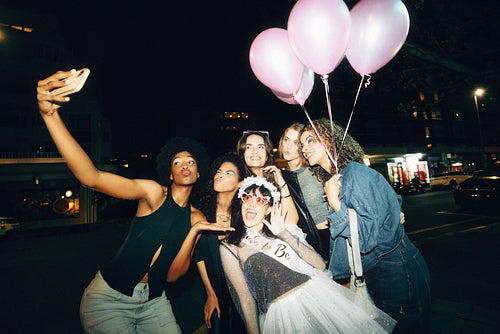 Group of friends celebrating a special night outdoors posing with balloons