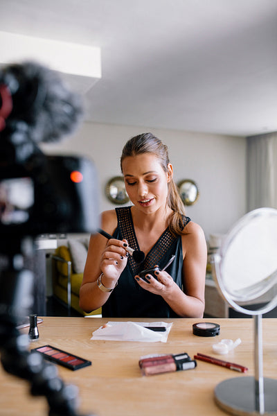 Young female vlogger recording a make-up video for her vlog.