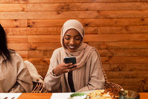 Muslim woman scrolling her smartphone in a restaurant