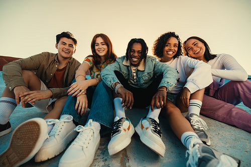 Gen Z friends sitting together outdoors, posing and smiling