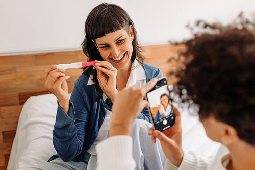 Cheerful young woman posing for a picture holding her pregnancy