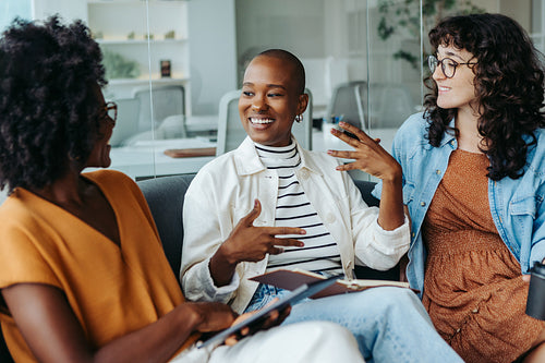 Business women engaging in a conversation on an office couch