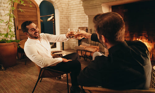 Two young men celebrating with whiskey glasses in a hotel