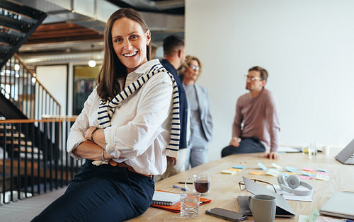 Female professional sitting in a boardroom with her team in the background