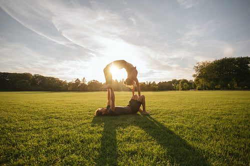 Young couple doing acrobatic yoga on lawn