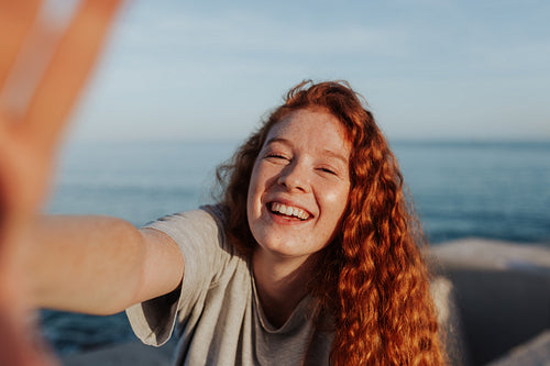 Cheerful young woman taking a selfie next to the sea