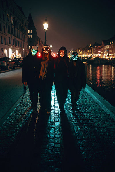 Friends wearing glowing neon masks during a Halloween street party at night