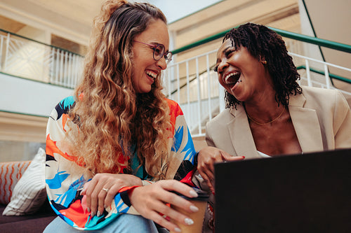 Young colleagues laughing together while sharing a cheerful moment at the office setting