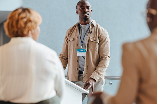Business man addressing an audience of professionals and leading a meeting at an expo