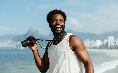 Smiling Brazilian man with camera on Ipanema Beach