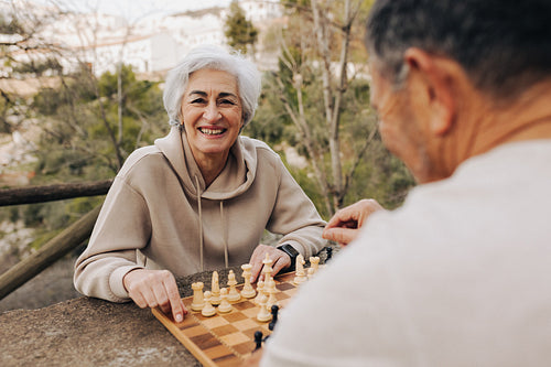Elderly couple playing a game of chess in a park