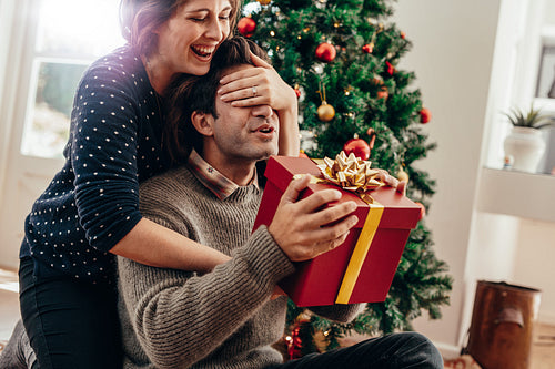 Young couple having fun celebrating Christmas with gifts.