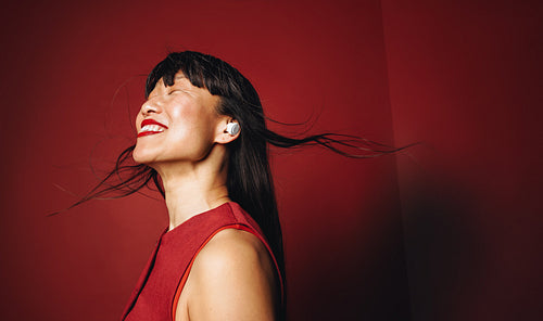 Mature woman enjoying music with wireless earbuds in vibrant studio portrait