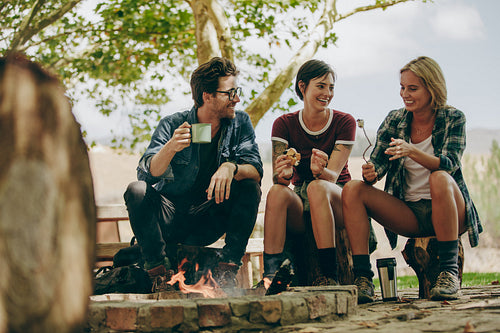 Friends toasting food on bonfire in the countryside