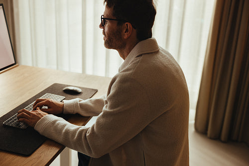 Small office desk setup, man working at his computer