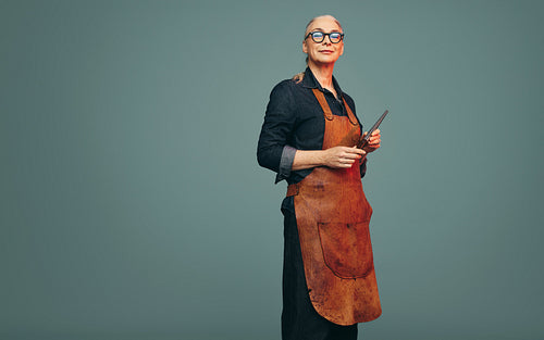 Cheerful jewellery maker holding a ring mandrel in a studio