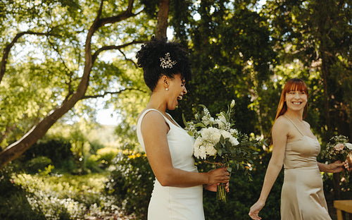 Joyful bridesmaids celebrating in a sunny green garden during a wedding event