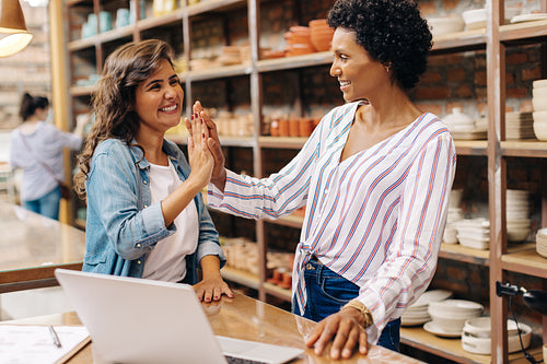 Shop owners high fiving each other in their ceramic store