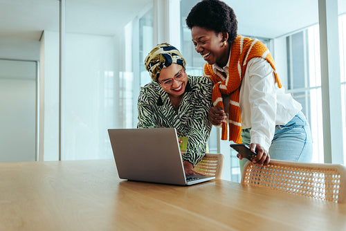 Diverse women collaborating in an aesthetic office, sharing ideas with a laptop