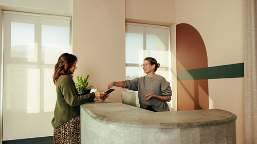Carefree receptionist assisting a woman with signing in to an of
