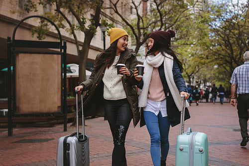 Tourist women walking on street with luggage bags