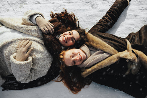Friends smile together while lying in snow