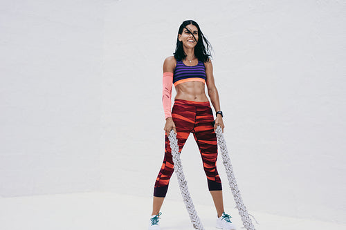 Athletic woman doing fitness training using battle ropes