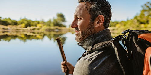 Mature man with backpack standing by the lake.