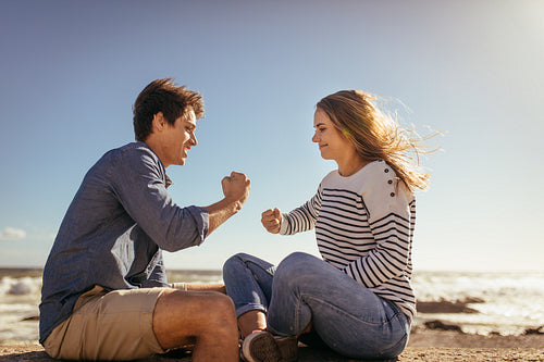 Couple playing games sitting on a sea wall 