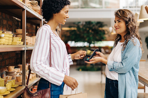 Ceramic store owner receiving a credit card payment from a customer
