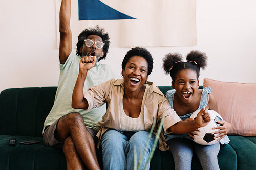 Family cheers as they watch an exciting football match at home