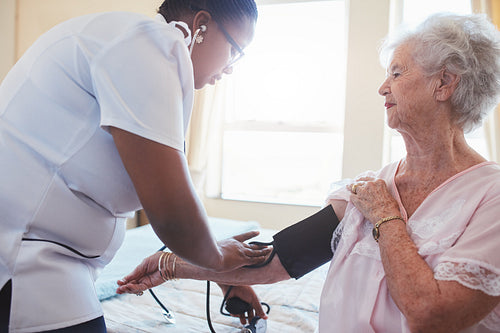 Home nurse taking patient's blood pressure