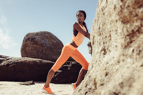 Fit black woman relaxing at beach after training session