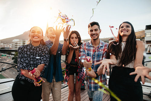 Young people enjoying rooftop party with confetti