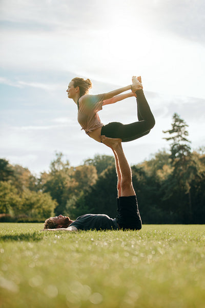 Flexible young couple doing acroyoga outdoors