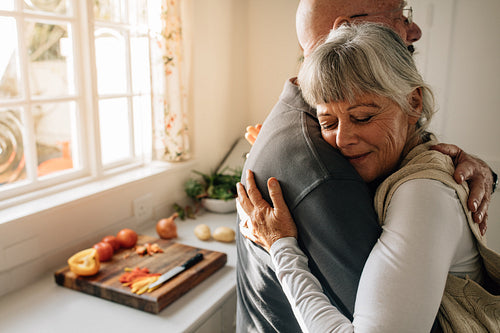 Senior man and woman embracing standing at home