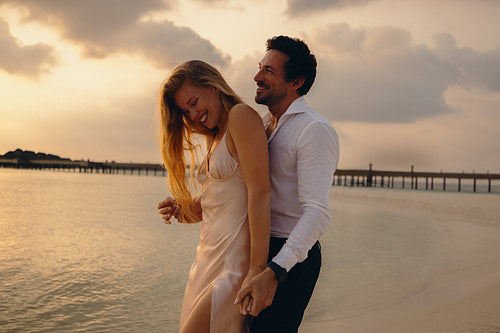 Playful couple enjoying honeymoon during sunset on tropical island beach