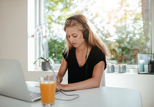 Serious young woman studying in kitchen