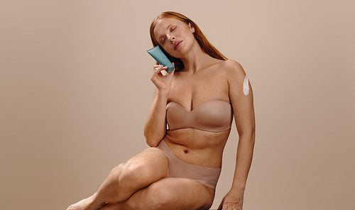 Woman applying skincare cream with a blue tube