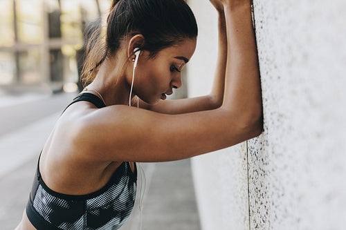 Female athlete training standing against a wall outdoors