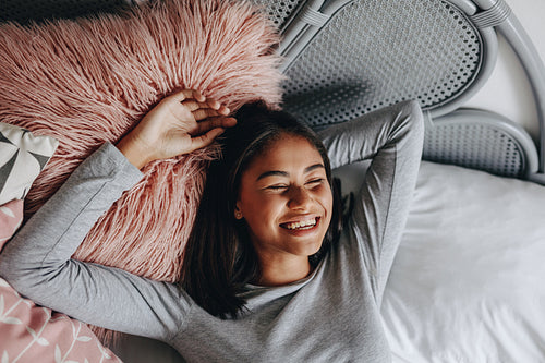 Top view of a smiling girl lying on bed