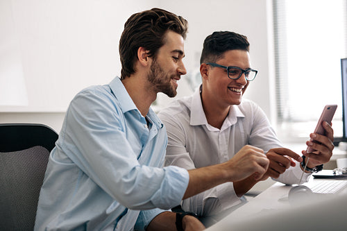 Office colleagues looking at mobile phone in office