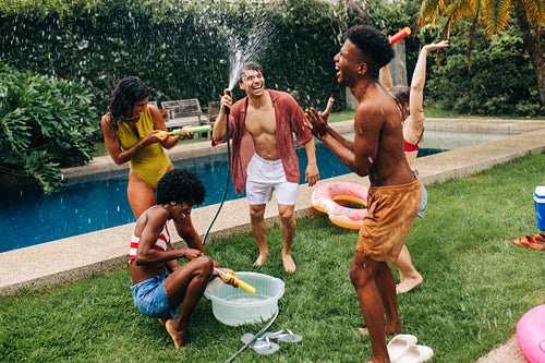 Friends enjoy water fight by pool