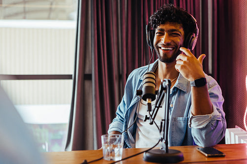 Happy male podcaster recording show with microphone and equipment