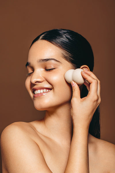 Applying makeup foundation: Female using a beauty blender on her face